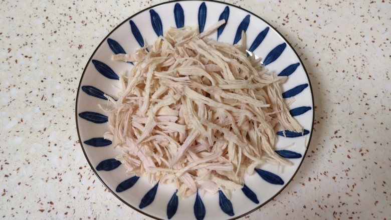 口水鸡丝,鸡胸肉煮好以后用凉水冲洗干净,用手撕开成鸡丝。