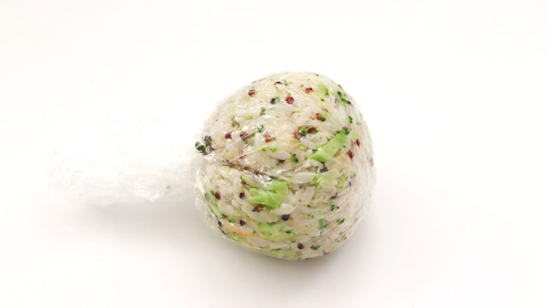 夏日藜麦甜虾时蔬饭团,把搅拌好的藜麦饭放入保鲜膜,借助保鲜膜把饭团包圆。