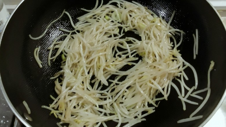 韭菜豆芽炒粉丝,重起油锅放入1汤匙食用油,油热后放入葱片炒香,放入豆芽翻炒片刻。
