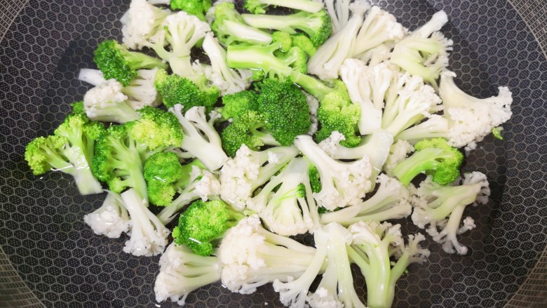 杂炒蔬菜,锅里放水烧开,下入西兰花和有机菜花,加入几滴食用油和少许盐,焯水1分钟关火。