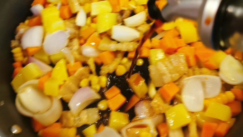 五花肉焖饭,放入玉米粒和洋葱翻炒,倒入酱油提味。