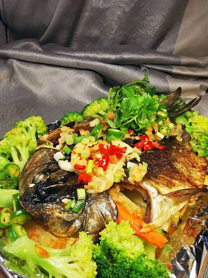 香烤鲫鱼,烤好的鲫鱼取出后,用西兰花围边,撒上香菜与小米椒。