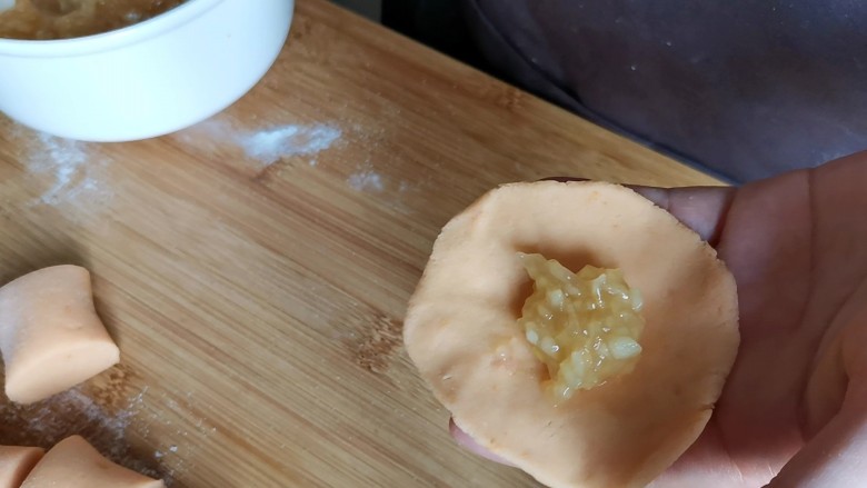红薯苹果馅饼,取一个剂子按成饼状,包入适量的苹果馅