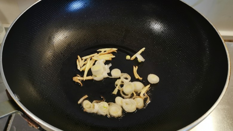 番茄炒鱼片,起油锅放入食用油,油热后放入姜丝炒出香味,放入葱片翻炒。