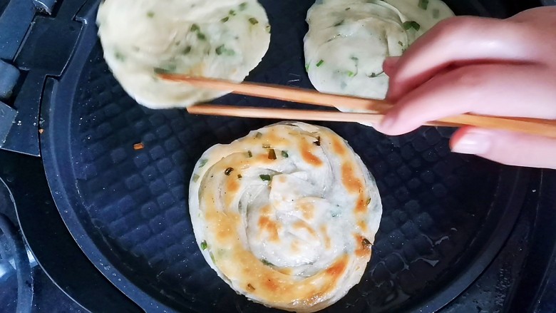 葱油蚕丝饼（饺子皮版）,电饼铛预热刷油，放入饼坯小火烙至两面金黄酥脆