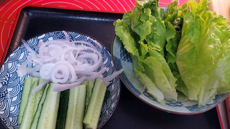 烤里脊肉,趁着静置时间，将生菜一片一片洗净。黄瓜去籽，切小长条。洋葱切丝泡冰水，增加脆度。整理好，也要放进冰箱。