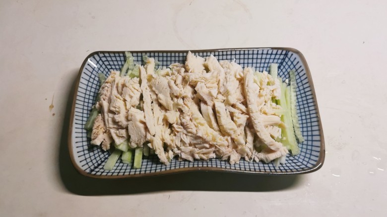 凉拌麻辣鸡丝,煮熟的鸡肉丝放到黄瓜丝上面。