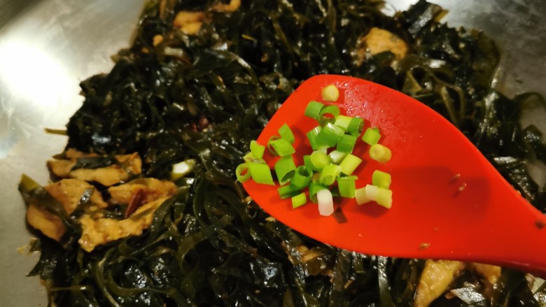海带炒肉片,撒上香葱碎增香,关火出锅。