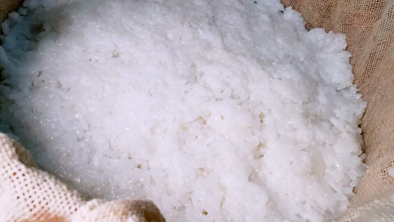 红枣切糕,蒸笼铺上屉布,先装一半的糯米饭,并压紧实一些