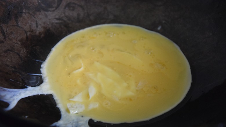 火腿青菜炒鸡蛋,热锅凉油,倒入蛋液煎至凝结,用锅铲切成小块