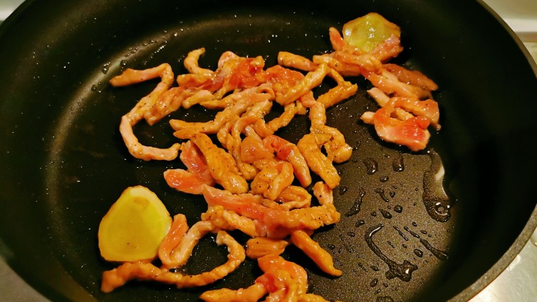 芹菜木耳炒肉丝,起油锅放入食用油,油热后放入姜片炒香,放入肉丝翻炒变色。