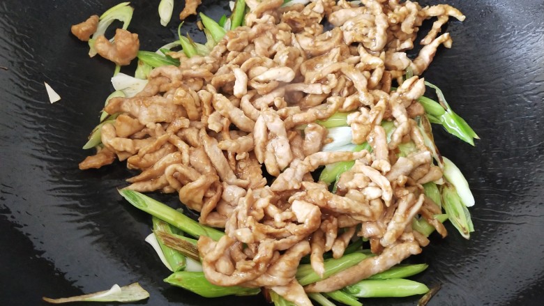 青葱炒肉丝,加入起先炒好的肉丝,翻炒均匀,滴入几滴酒增香,再加点水炒匀