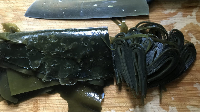 凉拌芝麻海带,放在案板上,用刀上切成细的海带丝