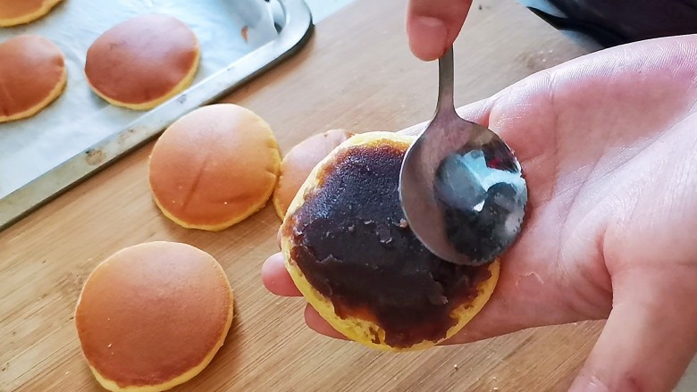 家常铜锣烧,所有的饼皮都烙好之后就可以抹豆沙了,取一个饼皮,抹上适量的豆沙