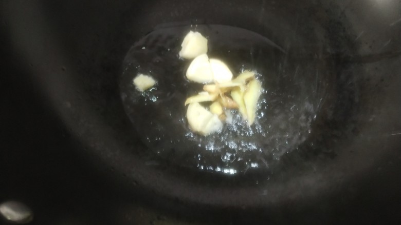 小炒鸡脯肉,锅里放油烧热,加蒜瓣和姜片炒香