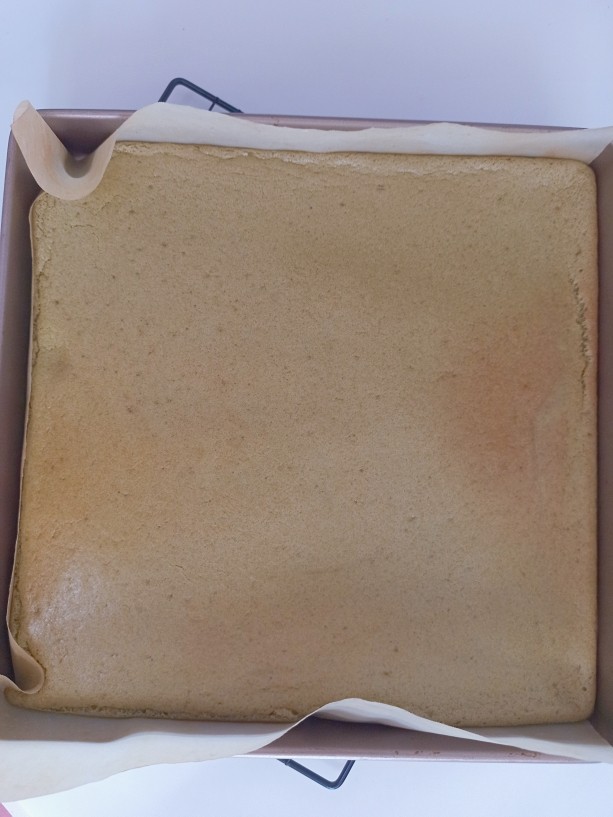 抹茶红豆蛋糕卷,把烤好的蛋糕取出来,上面盖上一层油纸翻过来