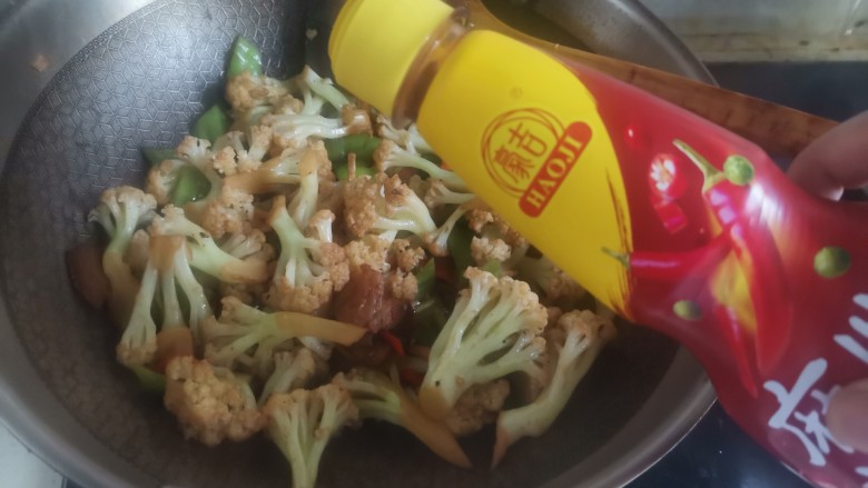 青椒炒花菜,然后加入一勺麻辣川香汁,翻炒均匀即可出锅