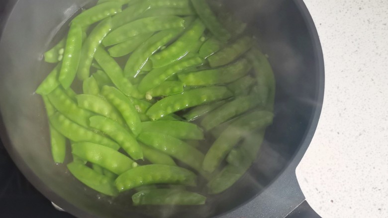 荷兰豆炒火腿,锅中烧开水,加少量油和盐,放入荷兰豆焯水1分钟捞出过凉。