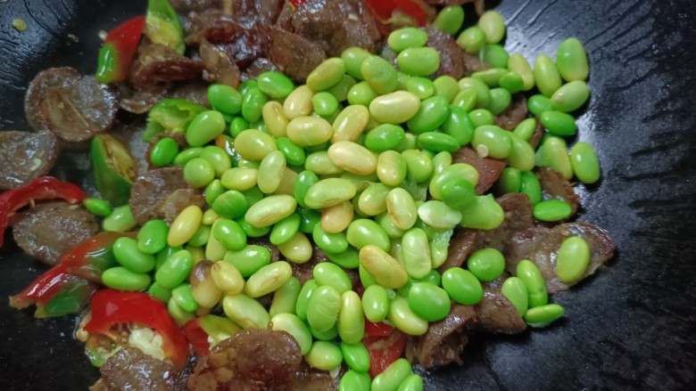 豆米炒腊肠,倒入豆米,炒匀至熟