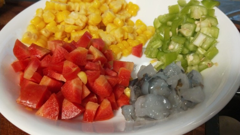 玉米虾仁蛋炒饭,胡萝卜切成丁,<a style='color:red;display:inline-block;' href='/shicai/ 61'>青椒</a>切丁,大虾切丁撒上白胡椒抓均匀。