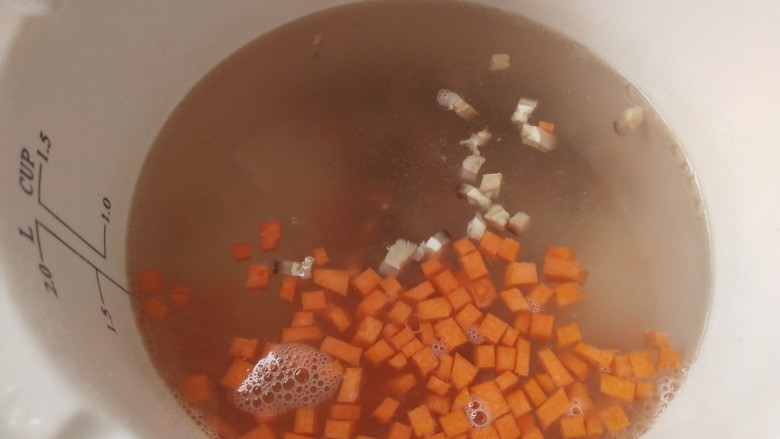 蟹肉粥,炖锅里一次性放入足量的开水,放入胡萝卜丁和香菇丁开始烧