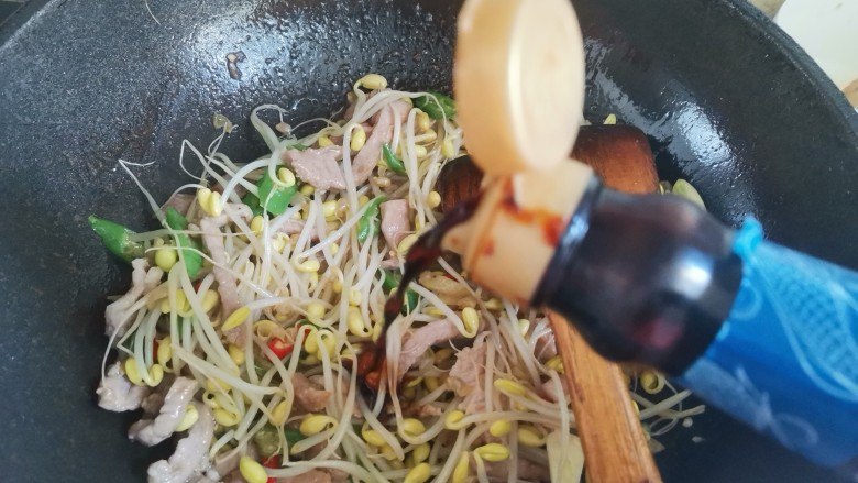 豆芽炒肉丝,加入一勺生抽,翻炒均匀