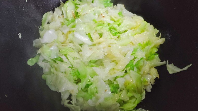 包菜粉丝炒鸡蛋,锅内添适量食用油,油热后下包菜,翻炒至变软体积变小