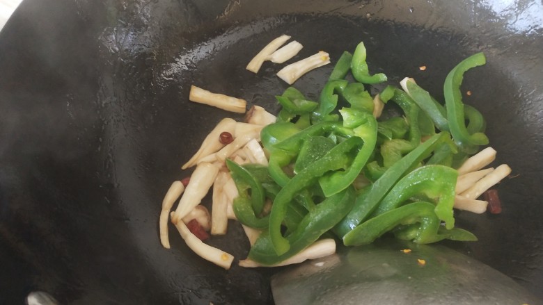 青椒爆炒牛里脊,倒入青椒炒匀,加少许开水烧一下