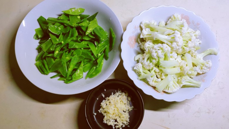 荷兰豆炒花菜,荷兰豆择去两边丝络，清洗干净切段，花菜一朵朵择下来清洗干净，蒜切碎备用。