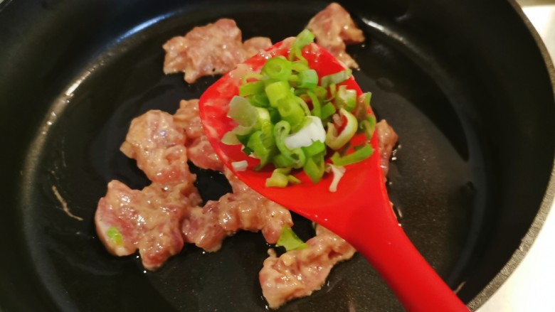 蘑菇炒肉片,加入部分葱碎翻炒。