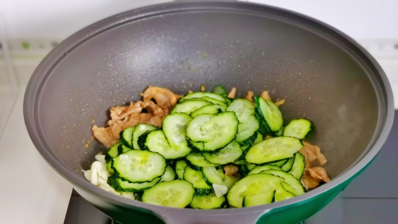 黄瓜炒肉片,倒入黄瓜片,蒜片。