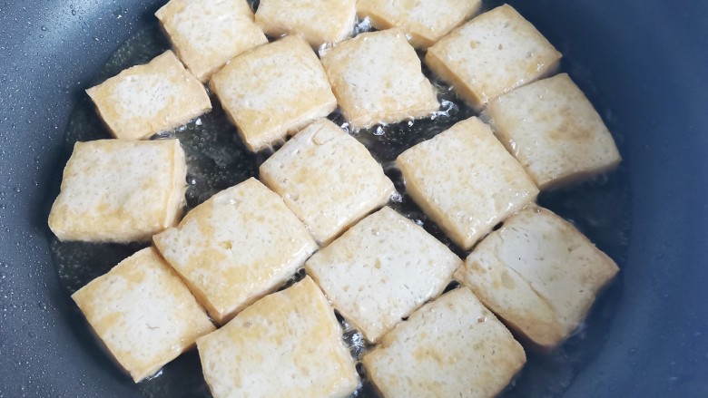 砂锅香菇豆腐煲,锅中热油,放入豆腐煎至金黄色后盛出。