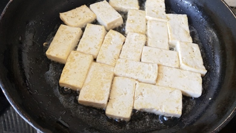 韩式辣酱豆腐,锅里放油烧热,把切成片的豆腐依次摆入锅中,煎至两面金黄