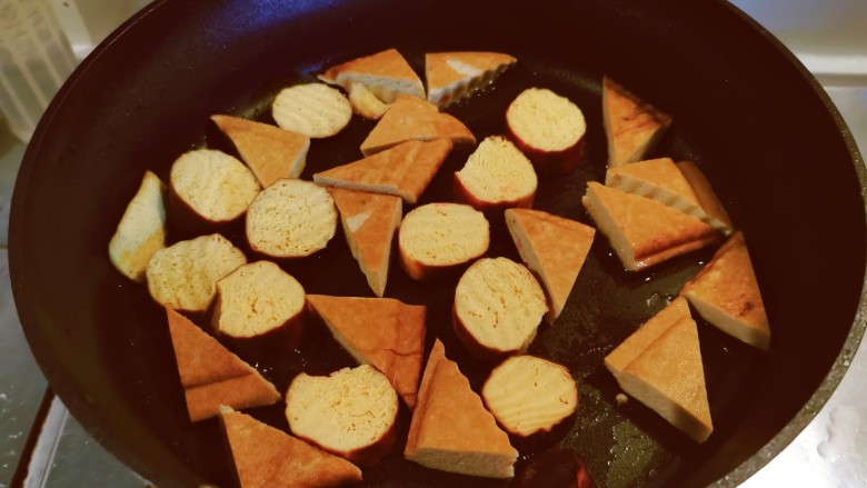 孜然煎豆干,锅中留下底油继续加热,放入豆干煎制。