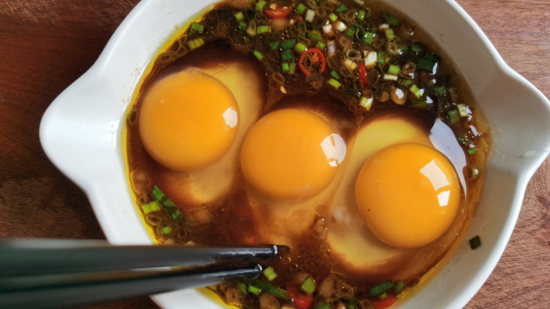 酱卧鸡蛋,用筷子轻轻的搅动,让部分蛋清和料汁混合,注意不要把蛋黄戳破。
