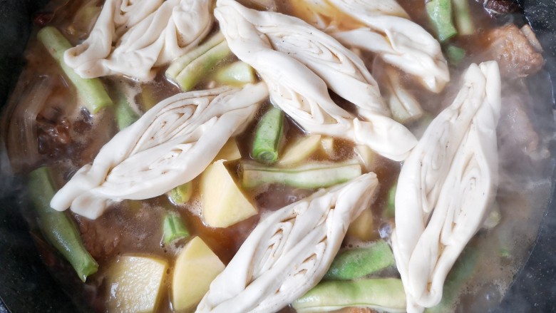 豆角焖卷子,将卷子铺在菜上,盖锅盖儿,闷上一会,大概10-15分钟。