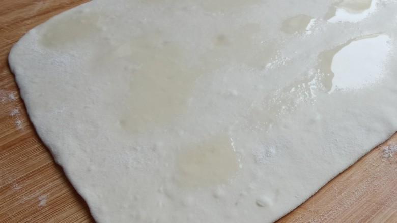 豆角焖卷子,将面团擀成长方形的面皮,在面皮上均匀地刷上一层食用油。