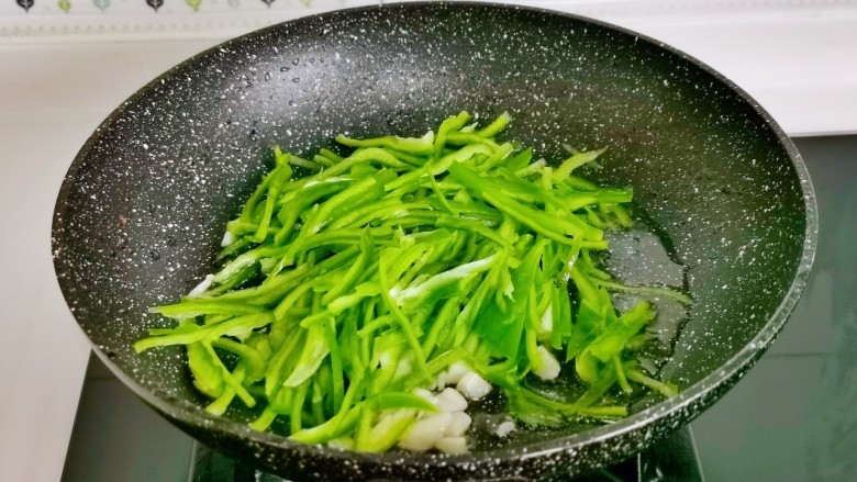青椒肉丝盖浇饭,经起油锅,加入蒜末煸炒,加青椒丝,葱丝。
