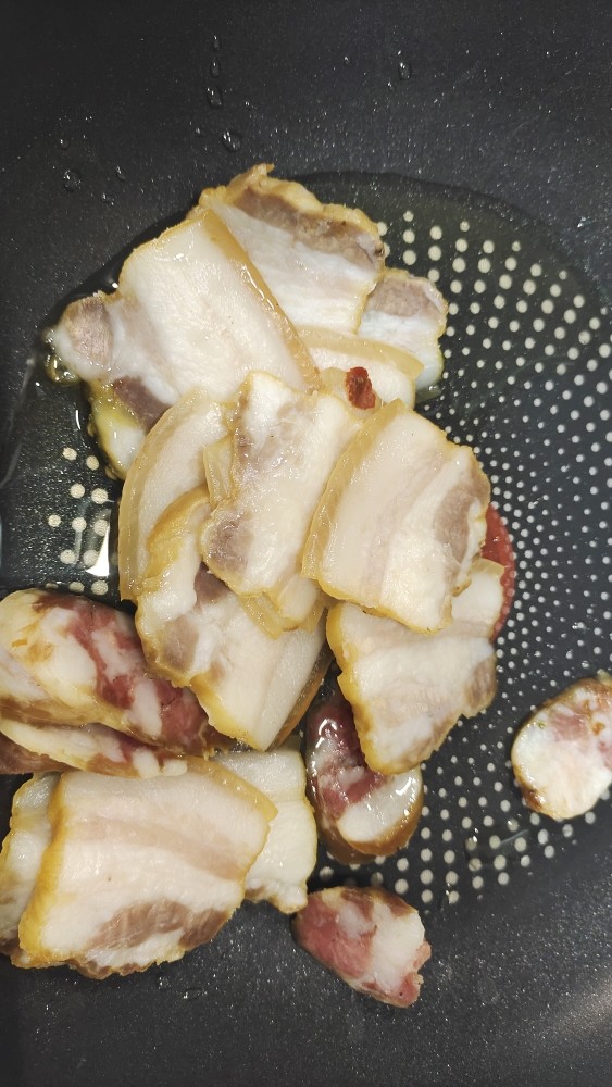 豆干炒腊肉,锅中烧油,加入腊肉煸炒出油脂