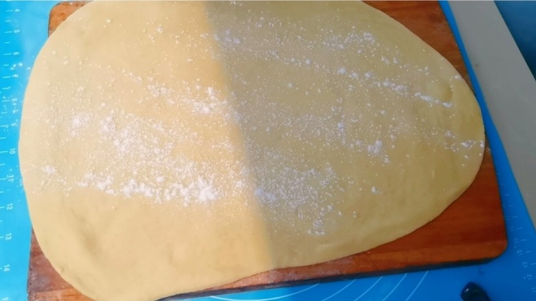 美味萨其马,擀好的面皮放在砧板上,再在面皮上撒上干面粉防粘。