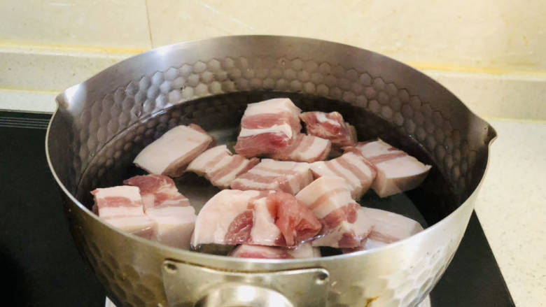 五花肉焖莲藕,锅中加入足量清水,冷水下入五花肉焯水。