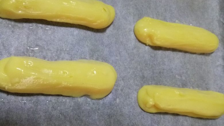 闪电泡芙,用标花袋(不用标花嘴)把面糊挤在垫上油纸的烤盘上,每个长度大约10-12cm,宽度2-3cm
