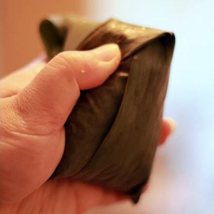 五花肉粽,余下的粽叶翻上去覆盖整个粽子,注意边角要折好,不然煮的时候糯米就会露出来了