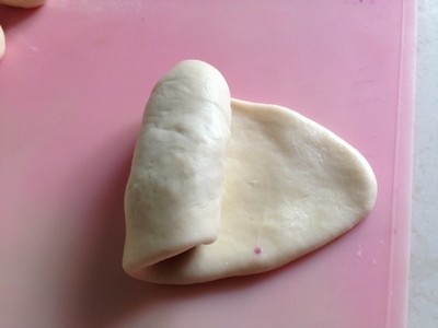 紫薯早餐包,从面皮顶端向下卷，包裹紫薯馅。