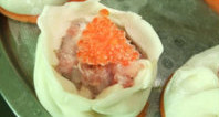 鲜虾烧卖,取一张<a style='color:red;display:inline-block;' href='/shicai/ 4346'>饺子皮</a>放在功夫茶杯上(也可放在手心),放入适量虾肉馅,将收口慢慢收拢,上面放点蟹子或青豆做装饰,将做好的鲜虾烧卖放在红萝卜片上。