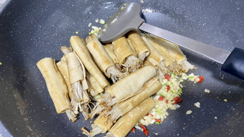 金针菇豆皮卷,锅中留底油,下蒜末小米辣葱白煸香,加入煎过的豆皮卷