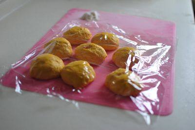 玉米油红萝卜培根面包,发酵好的面团,排除多余空气,分割成8份面团,滚圆后盖保鲜膜,静置15分钟。