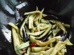 鱼香茄子,5.腌制过的茄子挤出水分，倒入锅中，加入红辣椒翻炒均匀。
