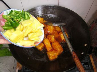 菠萝咕噜豆腐,将调好的番茄酱汁倒入锅内煮开,再放入事先煎好的豆腐块,然后放入菠萝块和青椒块,小心翻炒至青椒断生,收浓汁即可