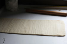 樱桃千层派 ,操作台撒适量手粉(高粉),用擀面杖轻敲、擀压,将面团擀成长条形。
